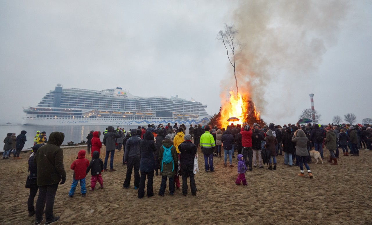 Ein Osterfeuer brennt am Elbstrand in Hamburg, während das Kreuzfahrtschiff Aida Perla vorbeifährt (Archivfoto). 