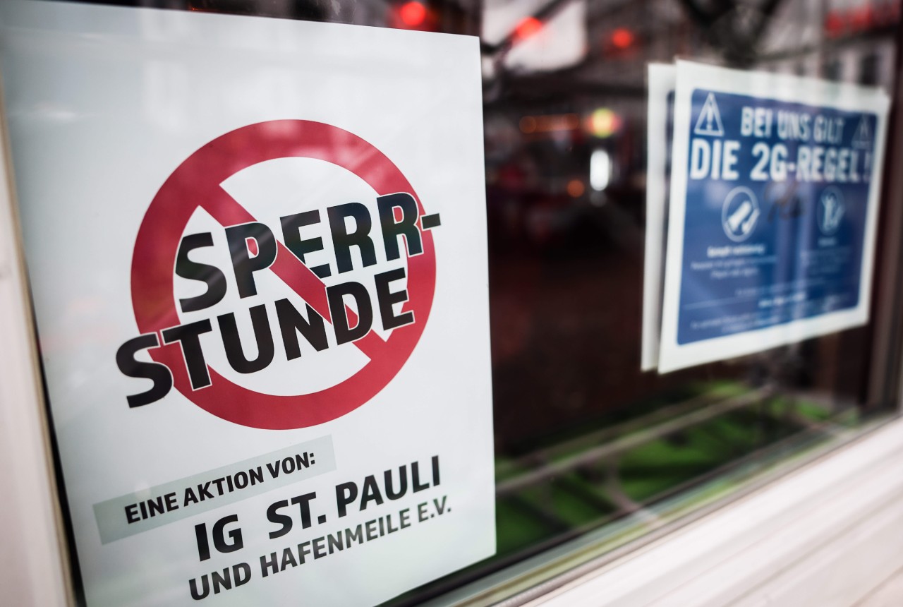 Eine Hinweisschild zur Abschaffung der coronabedingten Sperrstunde ist im Fenster einer Bar auf der Reeperbahn zu sehen. Dies soll nun durchgesetzt werden.