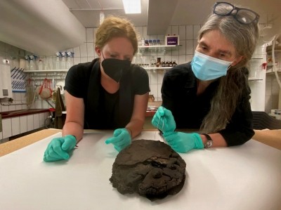 Lisa Renn (l.) und Doris Mührenberg (rechts) inspizieren den beim Luftangriff 1942 verschütteten Fund. Im Vordergrund sind die Verzierungen aus Zucker gut zu erkennen am hinteren Ende ist die Torte immer noch in Wachspapier eingeschlagen.