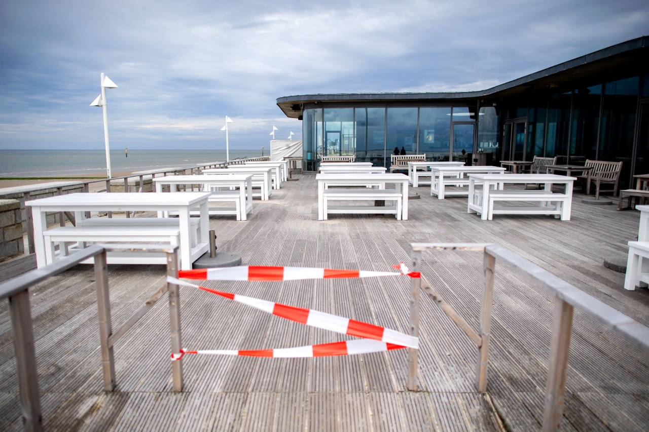 Zahlreiche leere Tische der Außengastronomie stehen auf der Terrasse der Milchbar an der Strandpromenade.