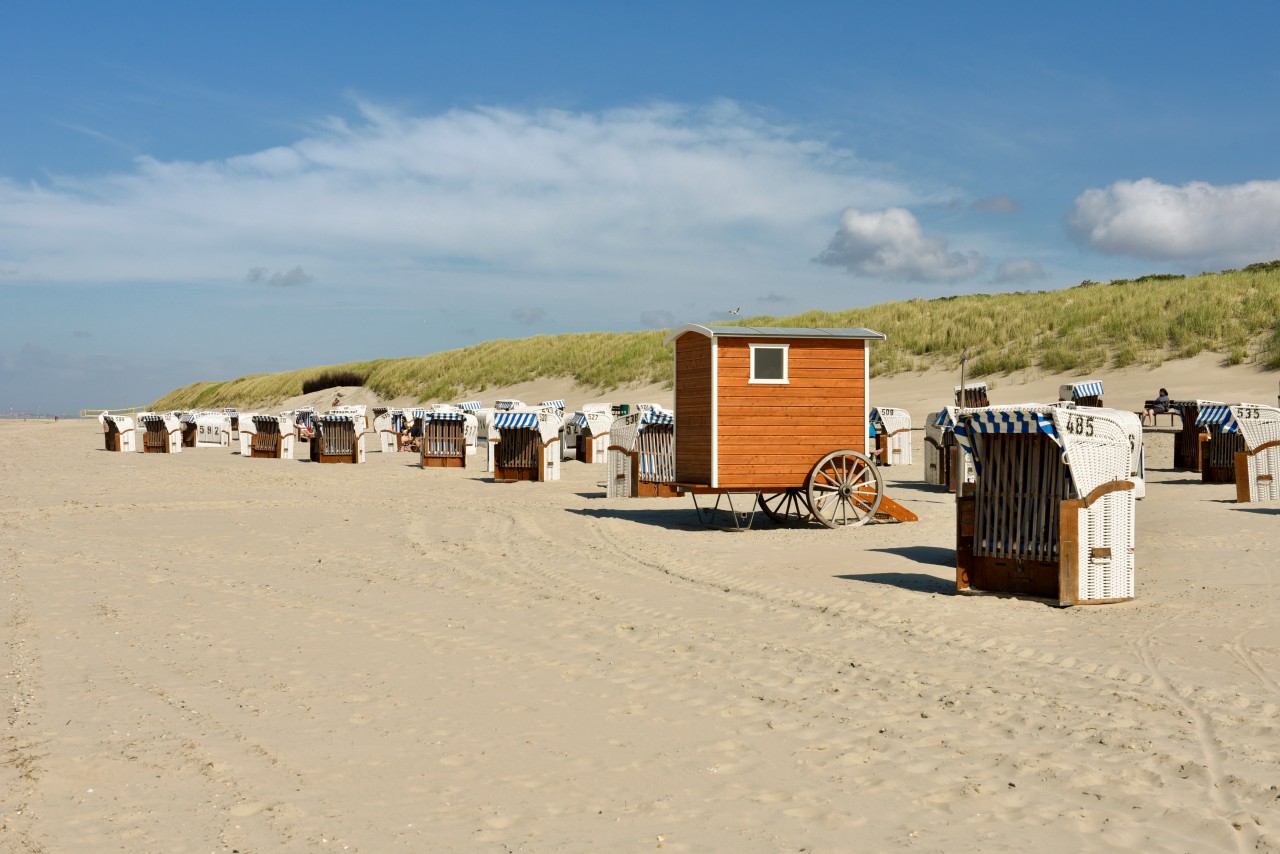 Spiekeroogs Badestrand mit weißen Strandkörben und einer Badekarre