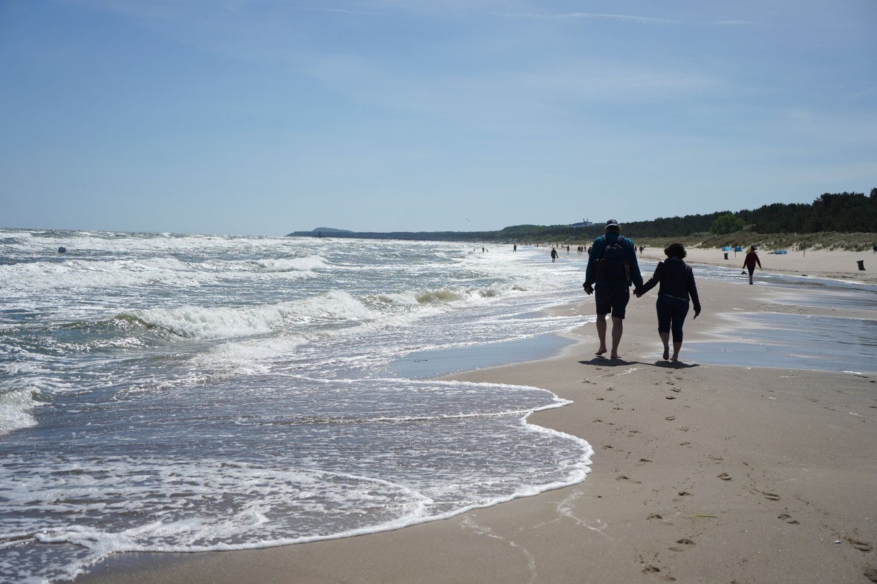 Spaziergänger gehen am Strand von Trassenheide auf Usedom entlang.