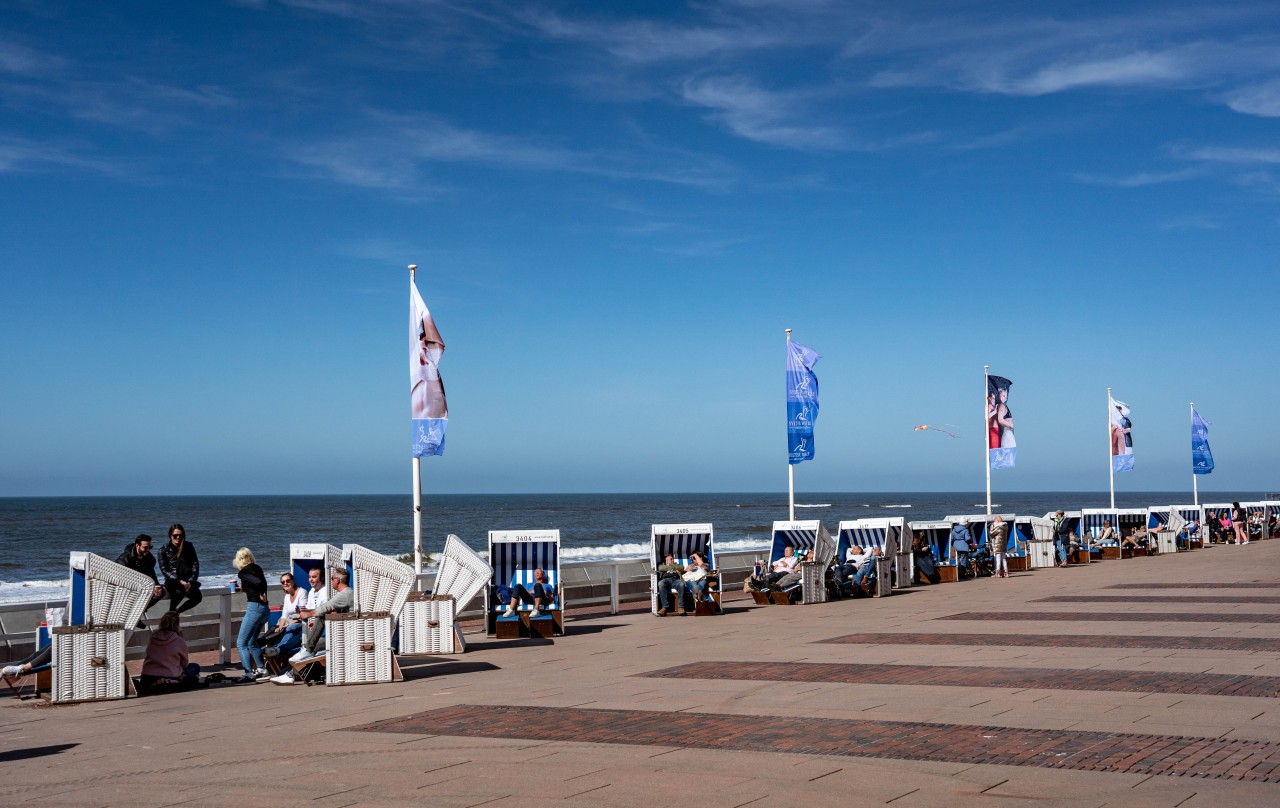 Menschen sitzen am Karsamstag an der Strandpromenade von Westerland auf Sylt.