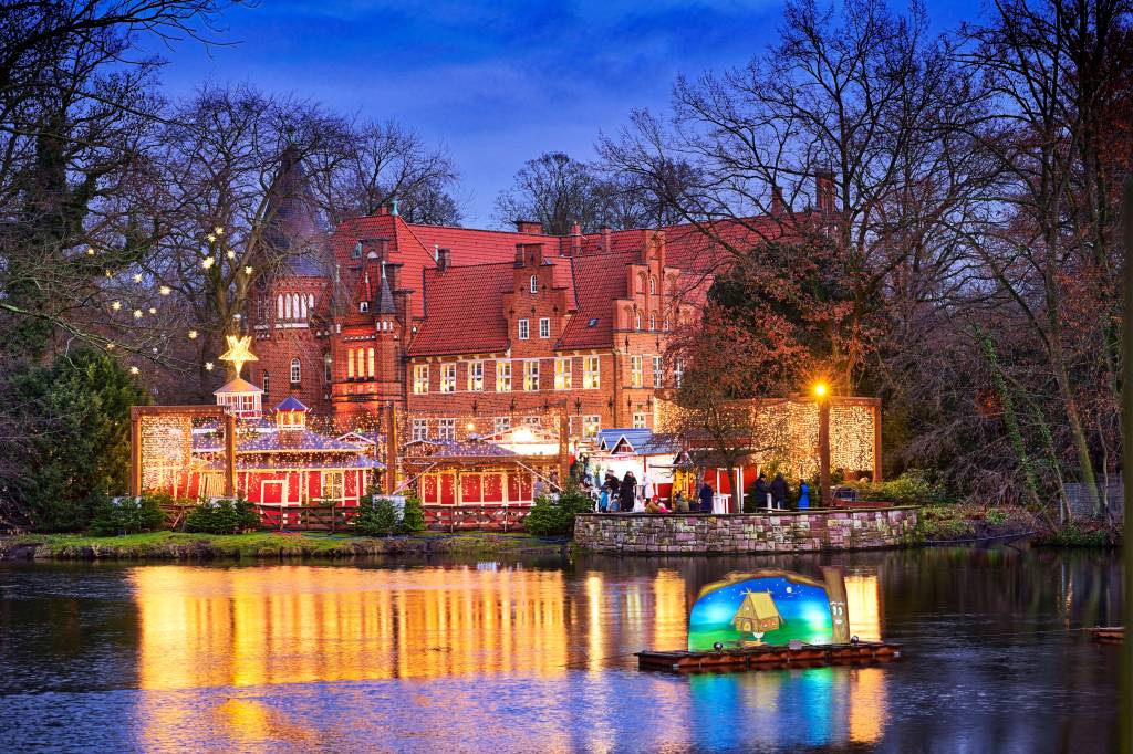 Blick auf das beleuchtete Schloss Bergedorf mit Wasserspiegelung.